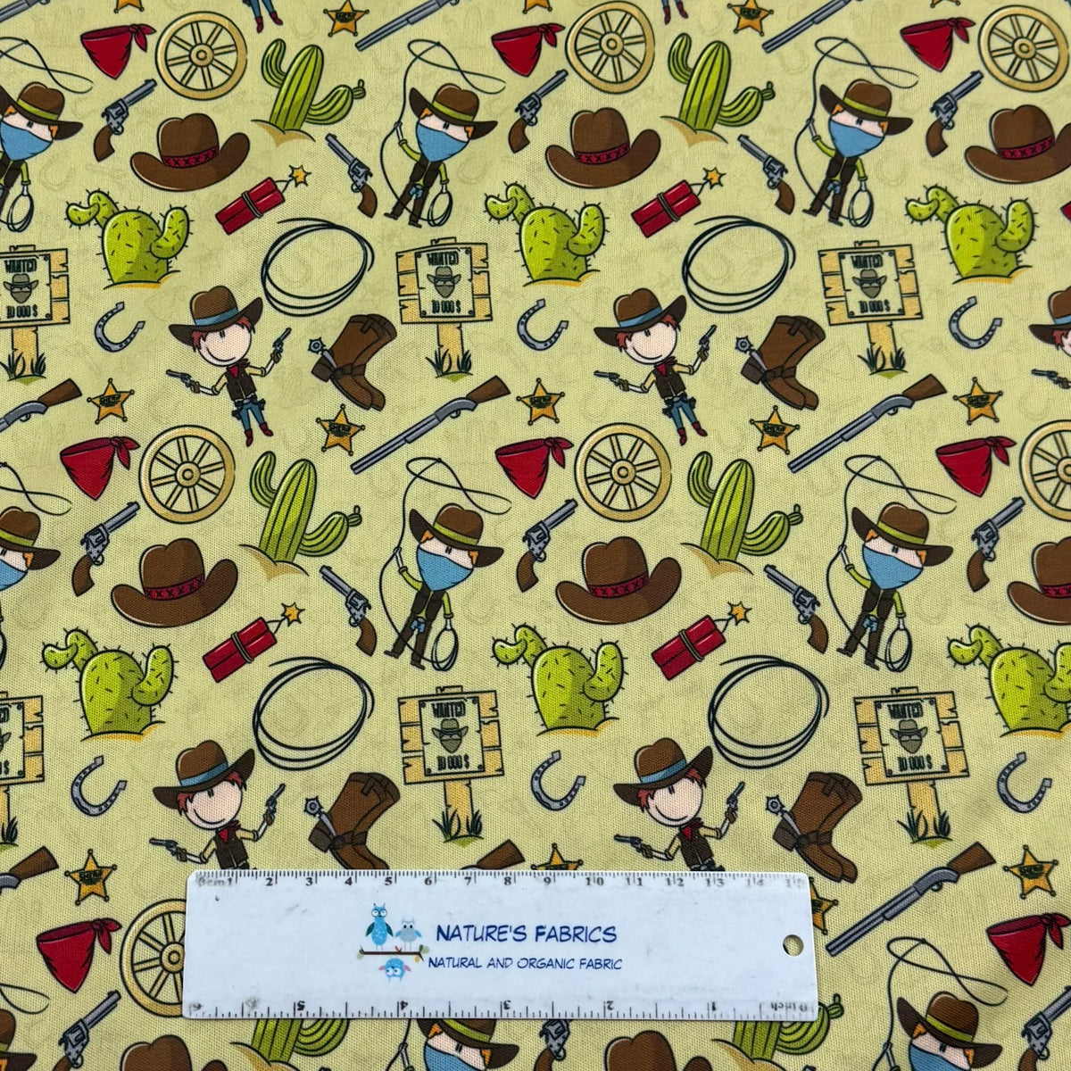 Cowboy-themed fabric with cacti, hats, guns, and wanted signs by Nature's Fabrics