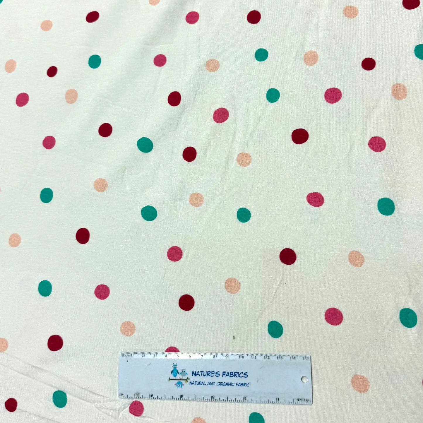Nature's Fabrics organic cotton fabric with colorful polka dots, ruler for scale, natural and eco-friendly textile