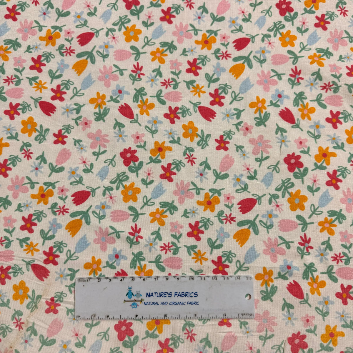 Nature's Fabrics floral print organic cotton fabric with colorful flowers and green leaves, ruler for scale