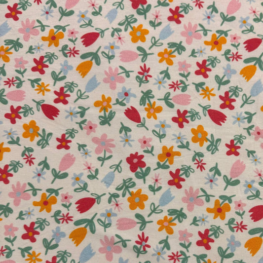 Nature's Fabrics floral print cotton fabric with small colorful wildflowers on a cream background