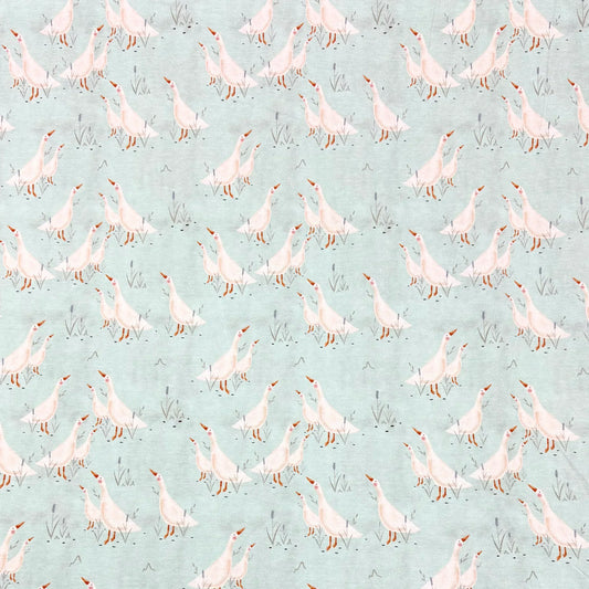 Nature's Fabrics light blue organic cotton fabric with a pattern of white geese and grass