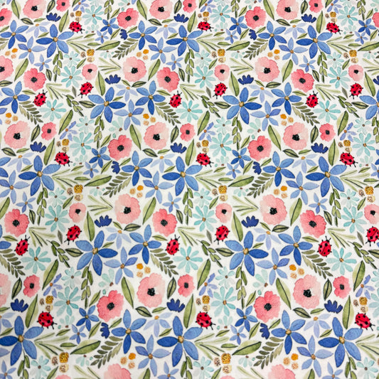 Nature's Fabrics floral print with pink and blue flowers, green leaves, and red ladybugs on white background