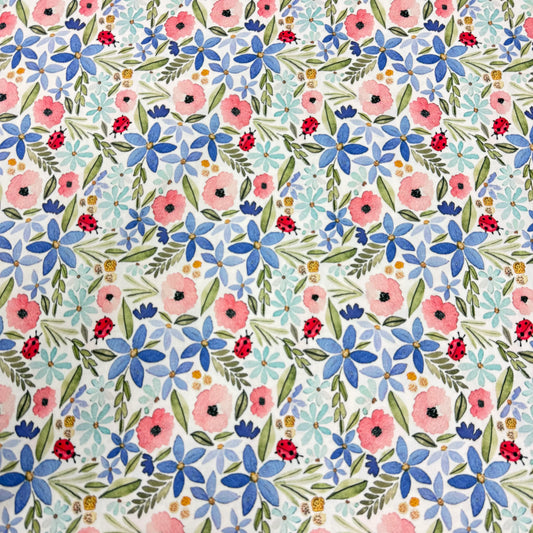 Nature's Fabrics floral print with pink and blue flowers, green leaves, and red ladybugs on white background