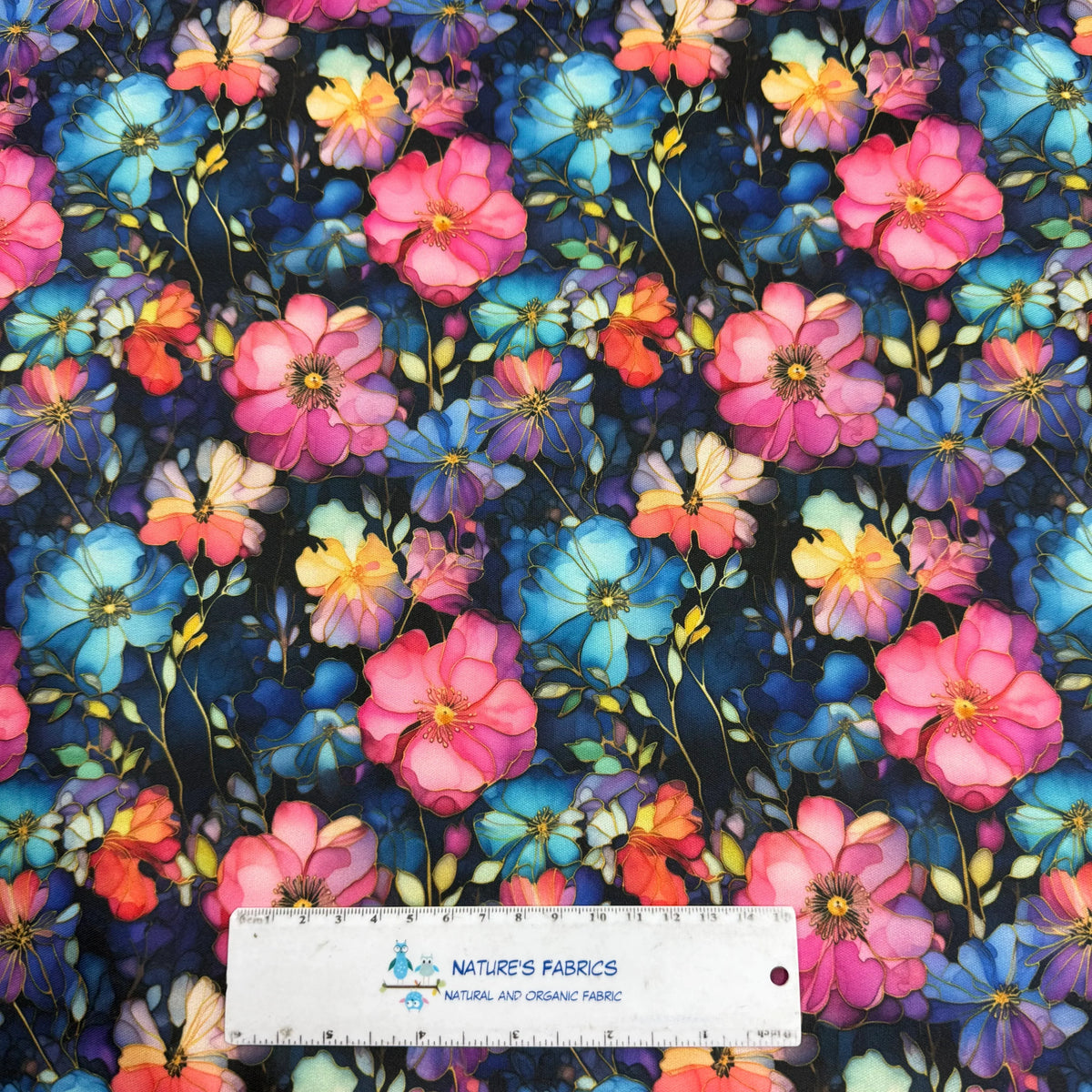 Vibrant floral print fabric with pink, blue, and yellow flowers on dark background, Nature's Fabrics