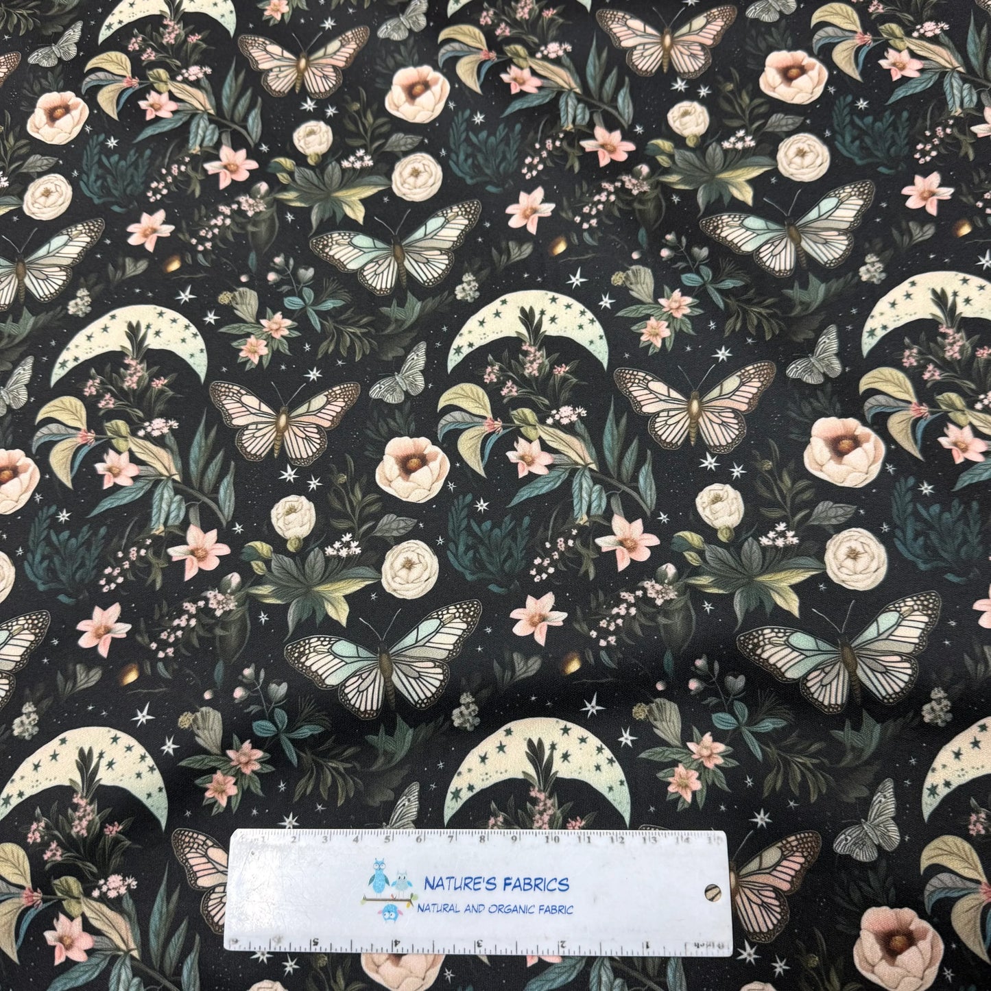 Nature's Fabrics: black fabric with butterflies, flowers, moons, stars, and greenery pattern
