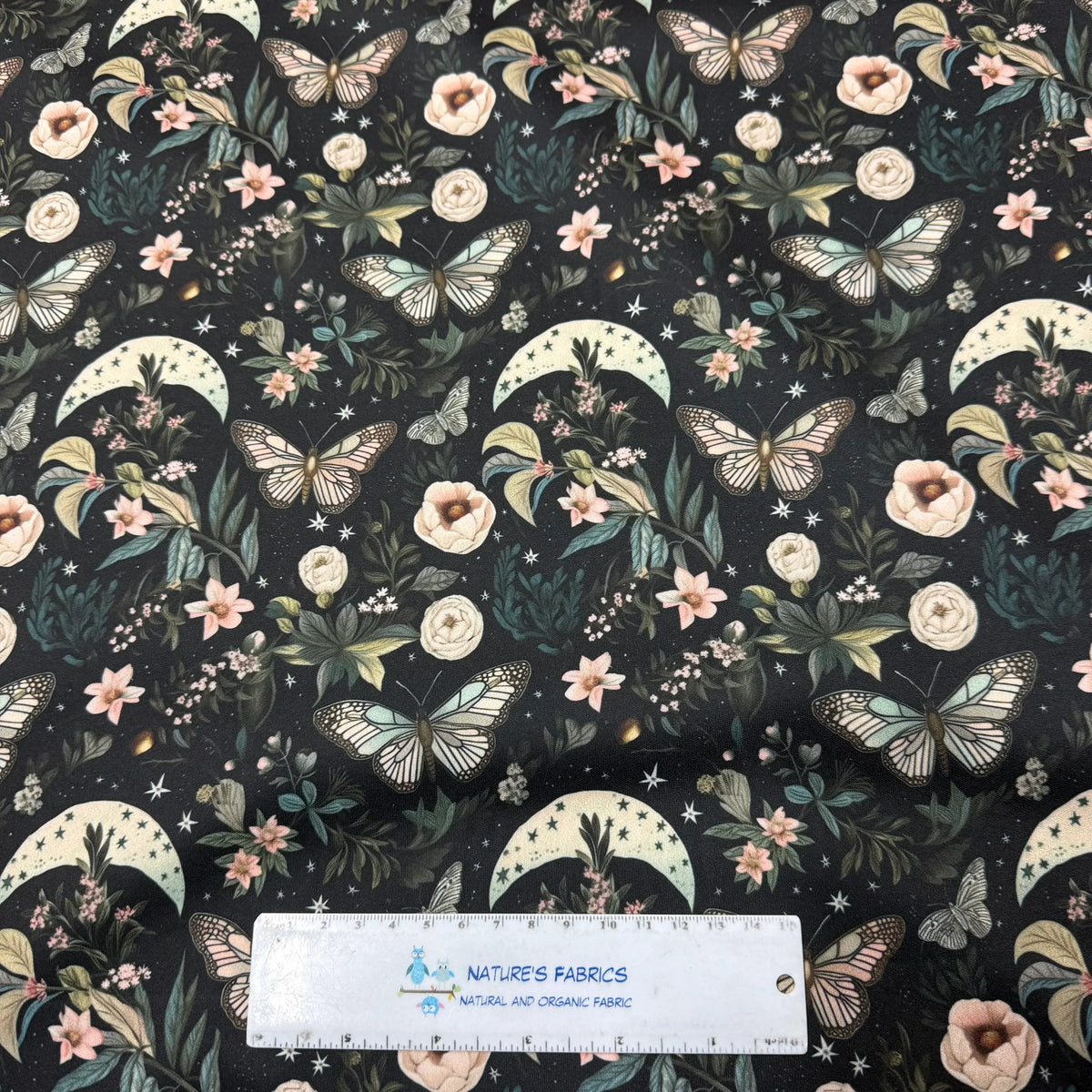 Nature's Fabrics: black fabric with butterflies, flowers, moons, stars, and greenery pattern