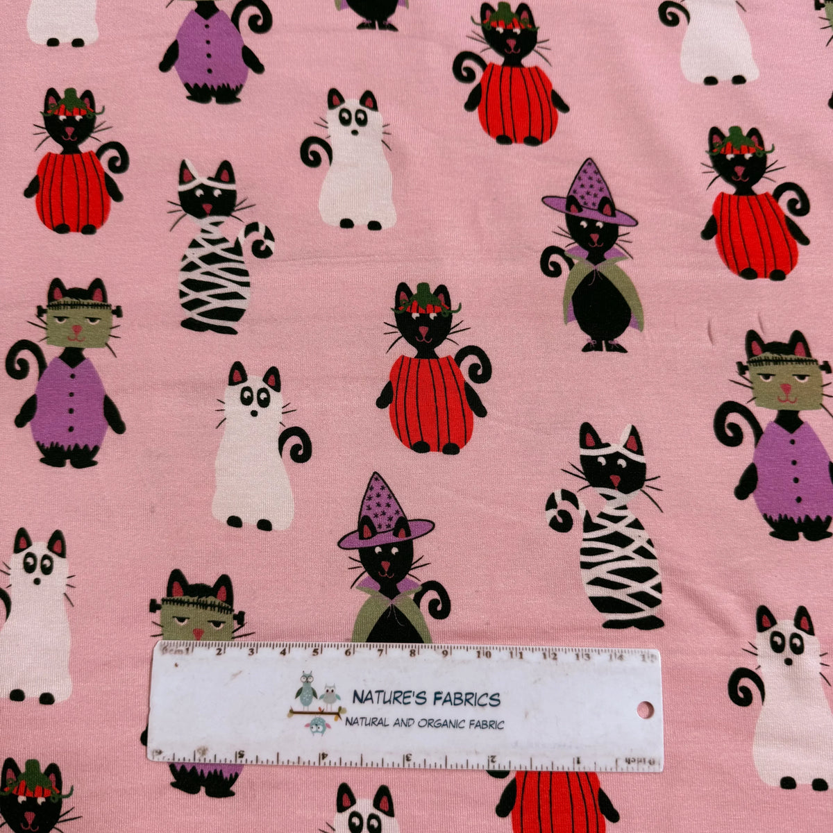Halloween cat print fabric by Nature's Fabrics, featuring spooky cats in costumes on pink background