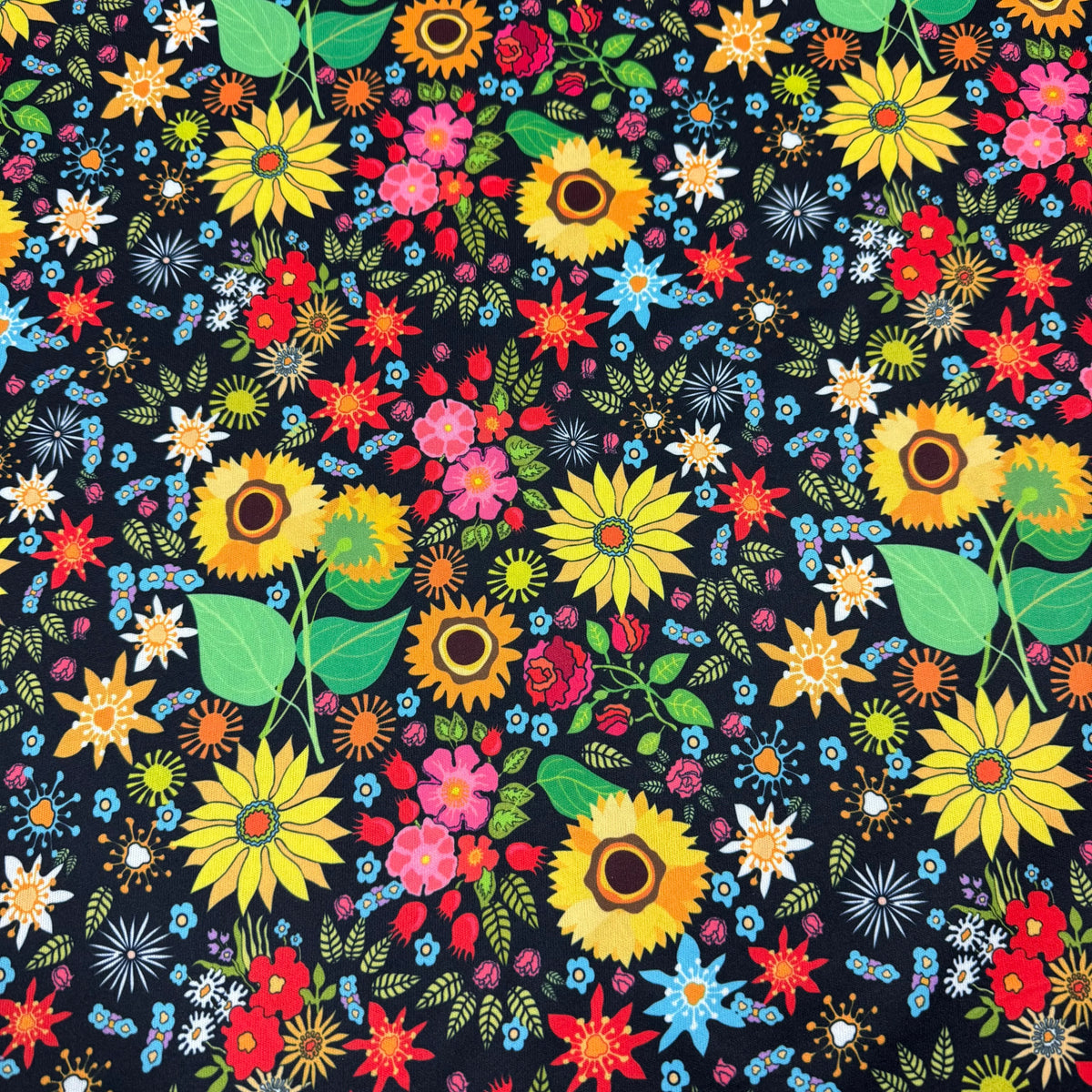 Colorful floral print fabric from Nature's Fabrics featuring yellow sunflowers and red blooms.