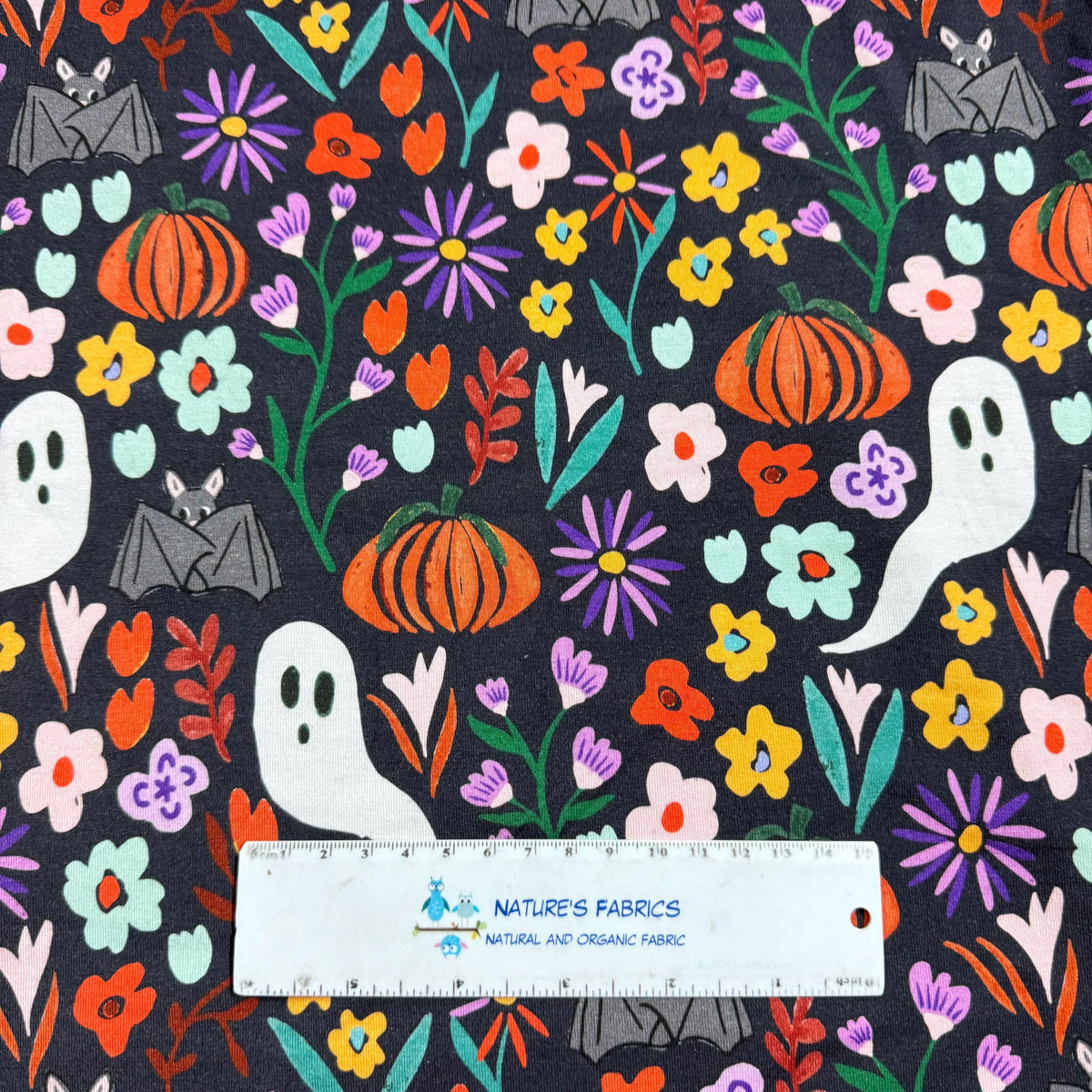 Halloween floral fabric with ghosts, bats, pumpkins, and flowers on dark background by Nature's Fabrics