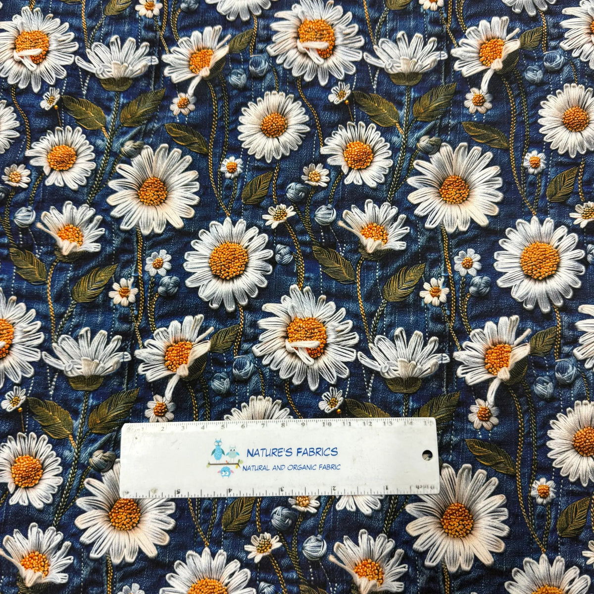Nature's Fabrics daisy floral pattern on blue organic cotton fabric with ruler for scale