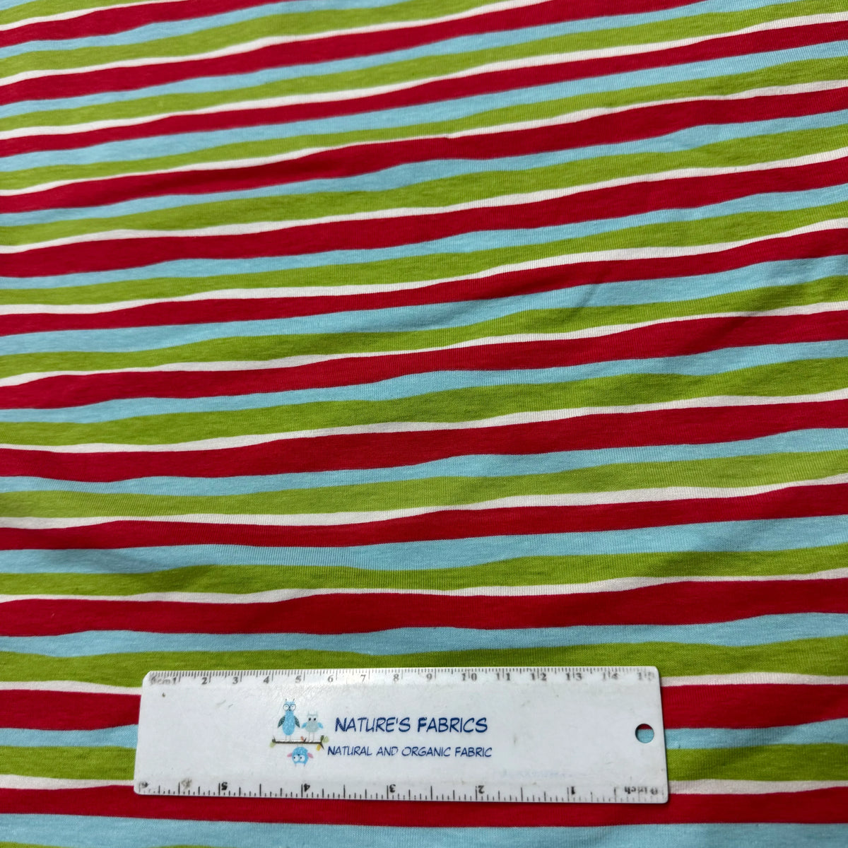 Nature's Fabrics multi-colored striped organic fabric with a ruler for scale.