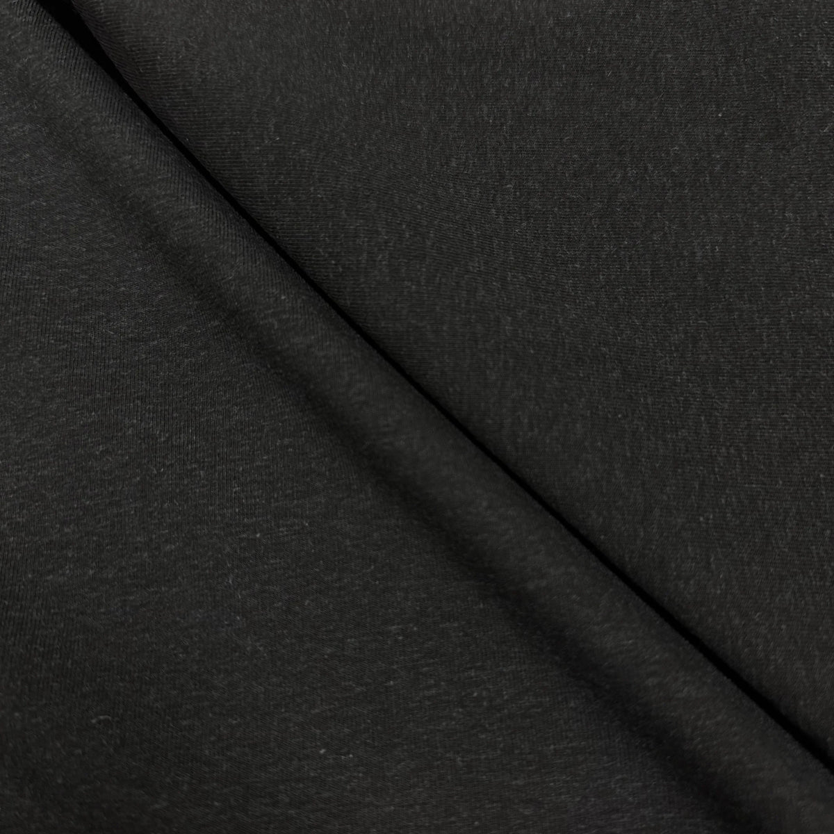 Close-up of smooth black organic cotton fabric with soft texture, perfect for sewing projects