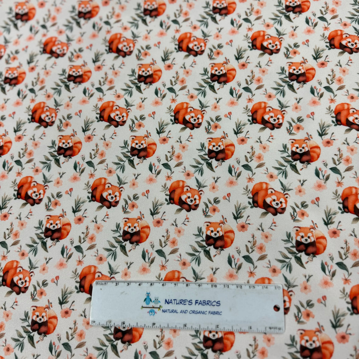 Red panda print organic cotton fabric by Nature's Fabrics with floral accents and ruler for scale