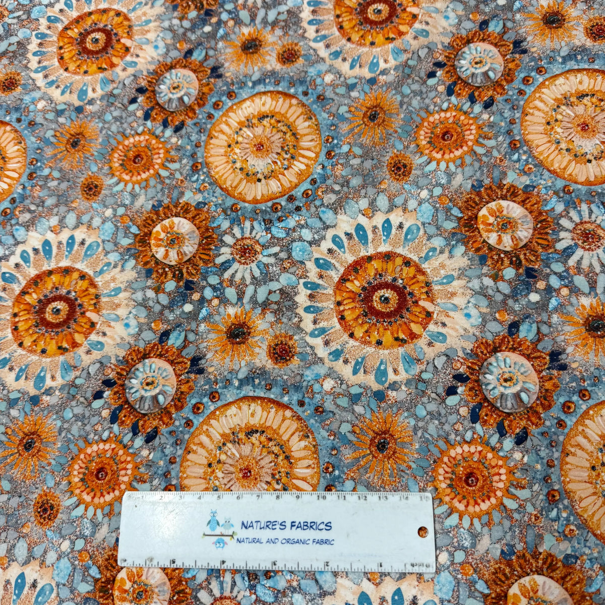 Nature's Fabrics organic cotton fabric with orange and blue floral pattern, shown with ruler for scale