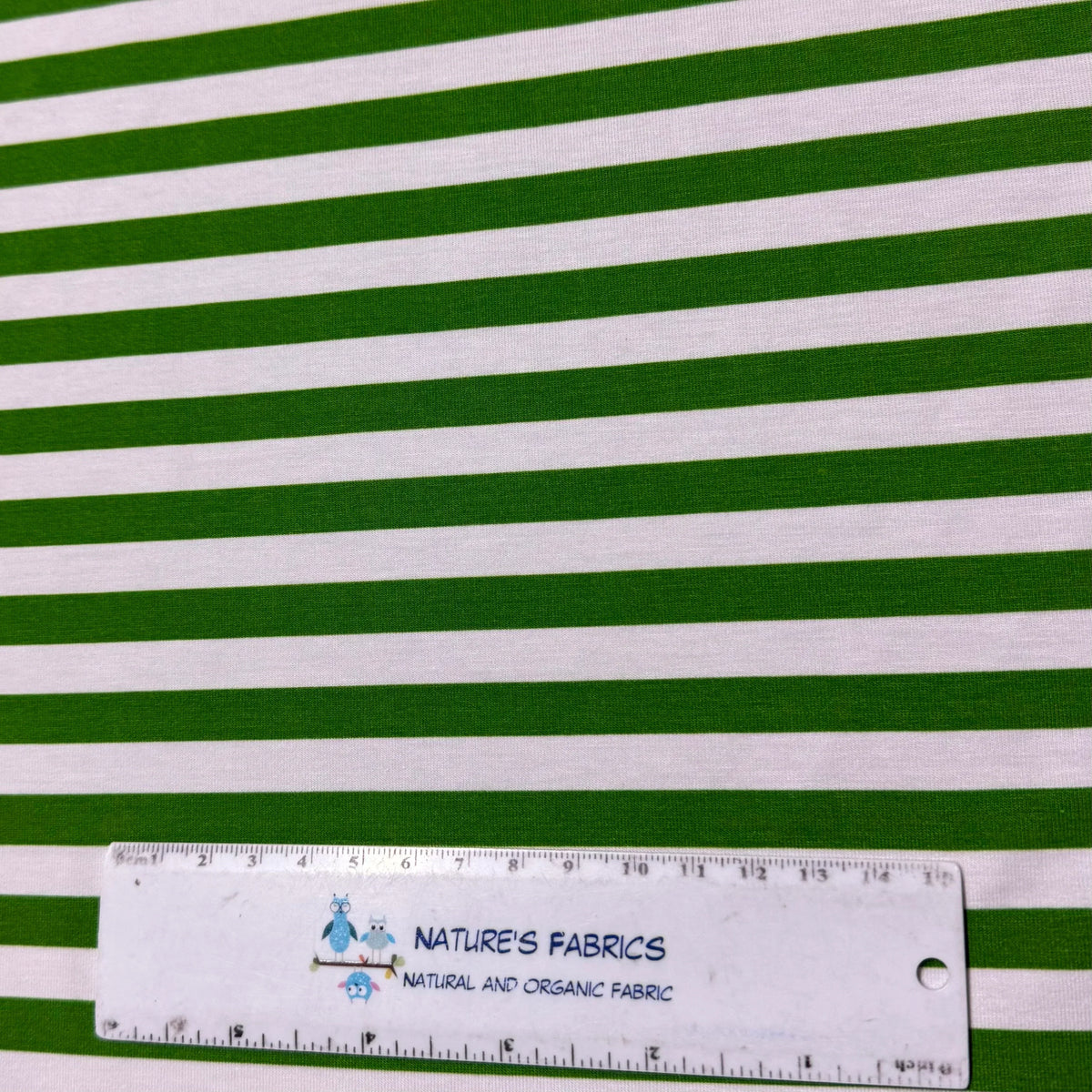 Green and white striped organic cotton fabric by Nature's Fabrics, natural and organic fabric with ruler for scale