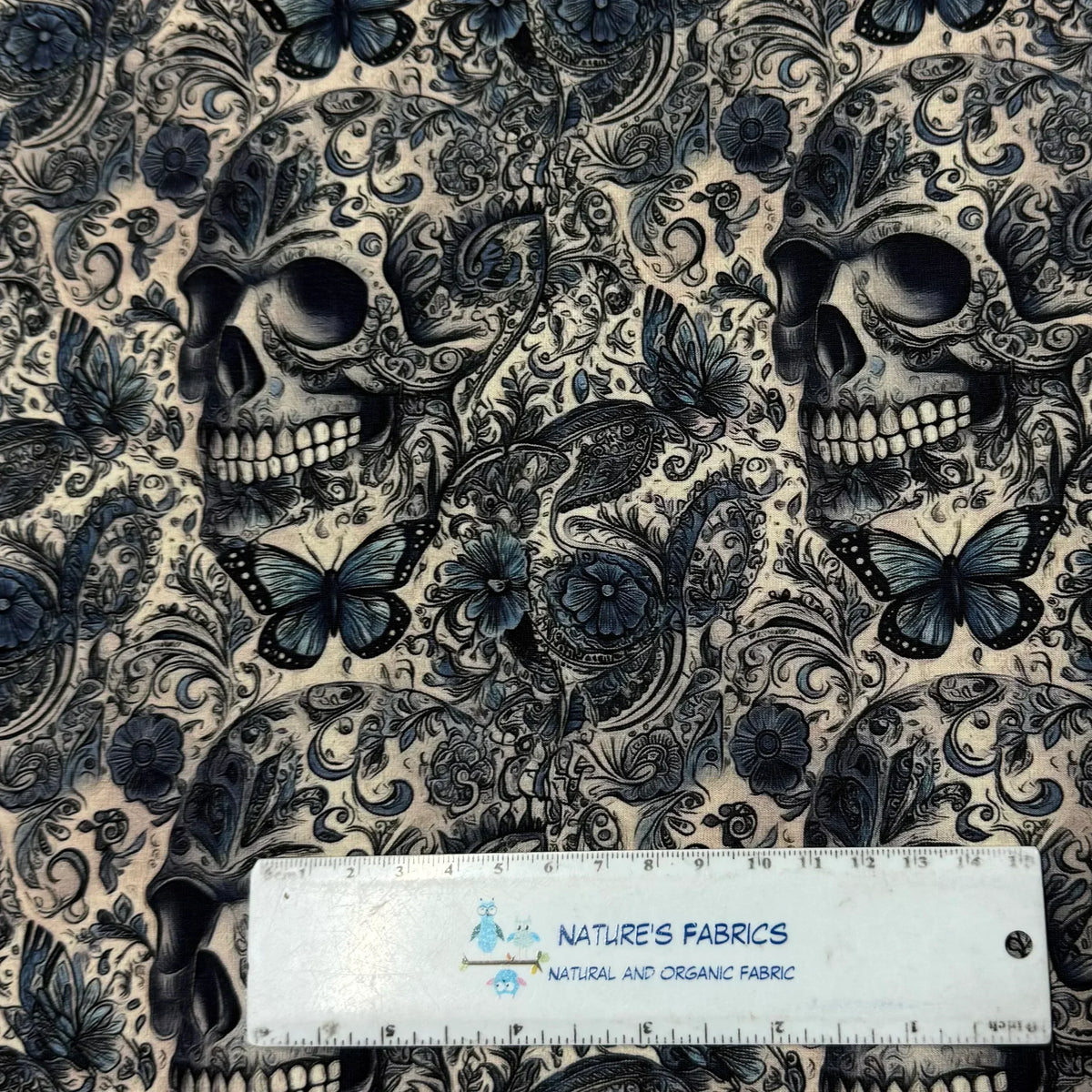 Nature's Fabrics skull and butterfly print fabric, organic cotton, dark blue floral design with ruler for scale