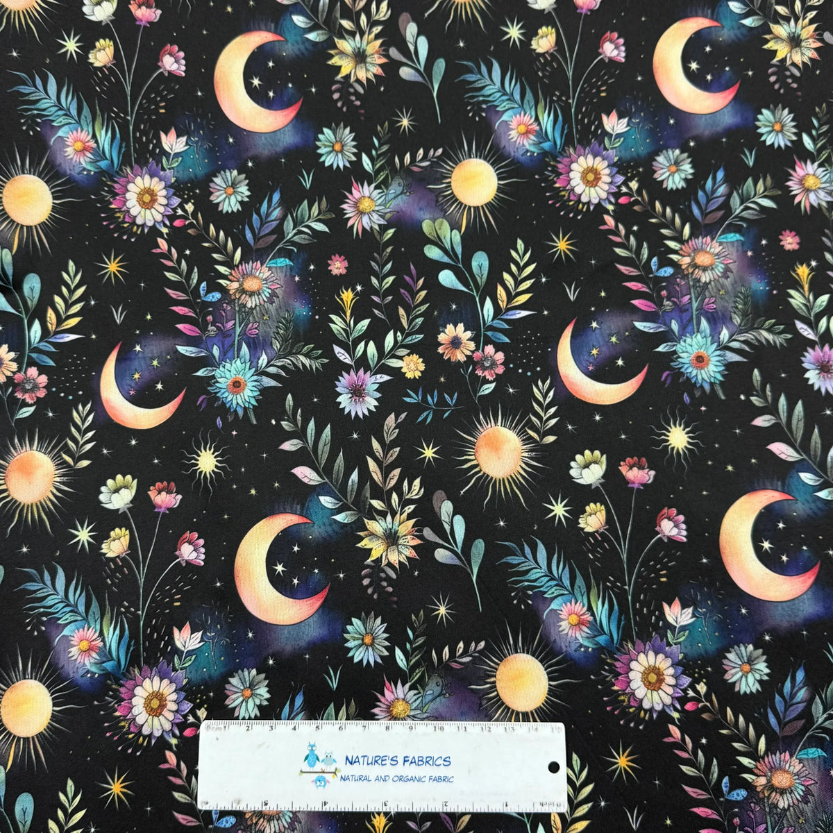 Nature's Fabrics celestial floral print with moons, stars, and suns on dark background