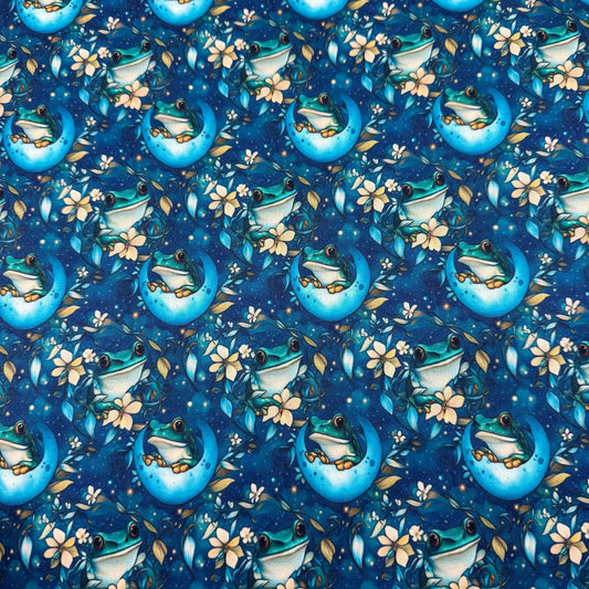 Nature's Fabrics blue fabric with whimsical frogs on crescent moons and white flowers.