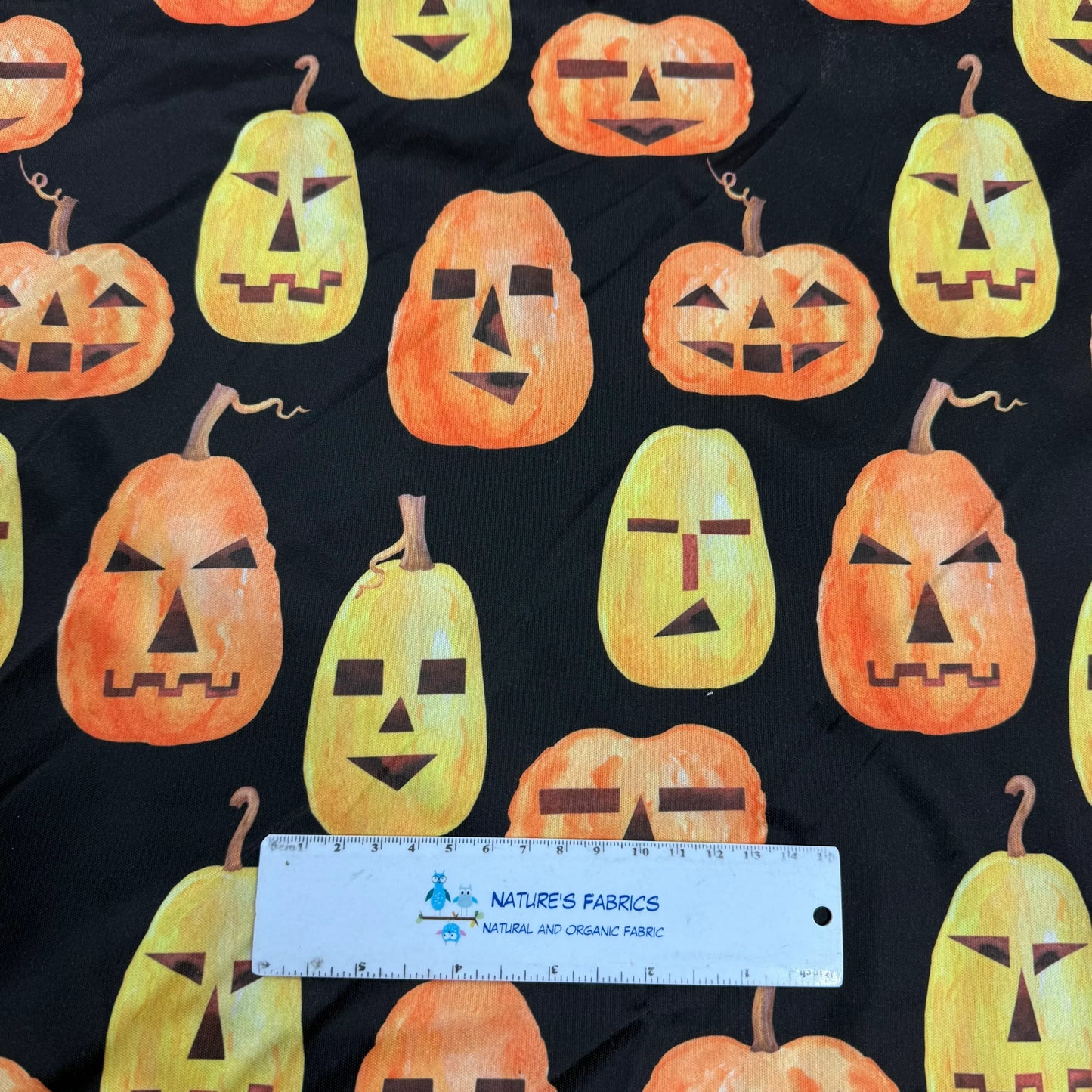 Halloween pumpkin fabric by Nature's Fabrics, featuring orange jack-o'-lanterns on black background