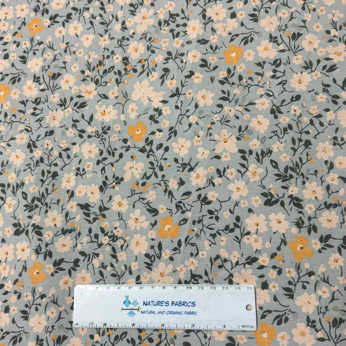 Nature's Fabrics floral print organic cotton fabric with cream, yellow flowers, green leaves on gray background