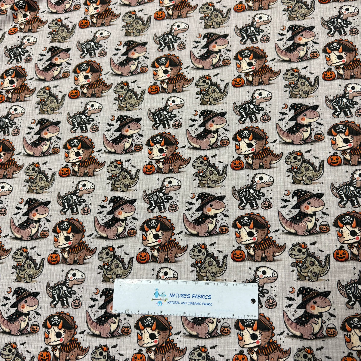Halloween dinosaur print fabric by Nature's Fabrics, featuring cute dinos in costumes and pumpkins