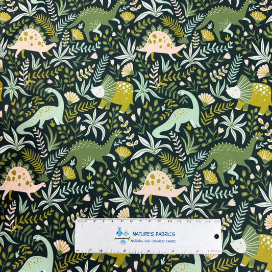 Nature's Fabrics dinosaur print organic cotton fabric with green, pink, and yellow prehistoric creatures on dark background