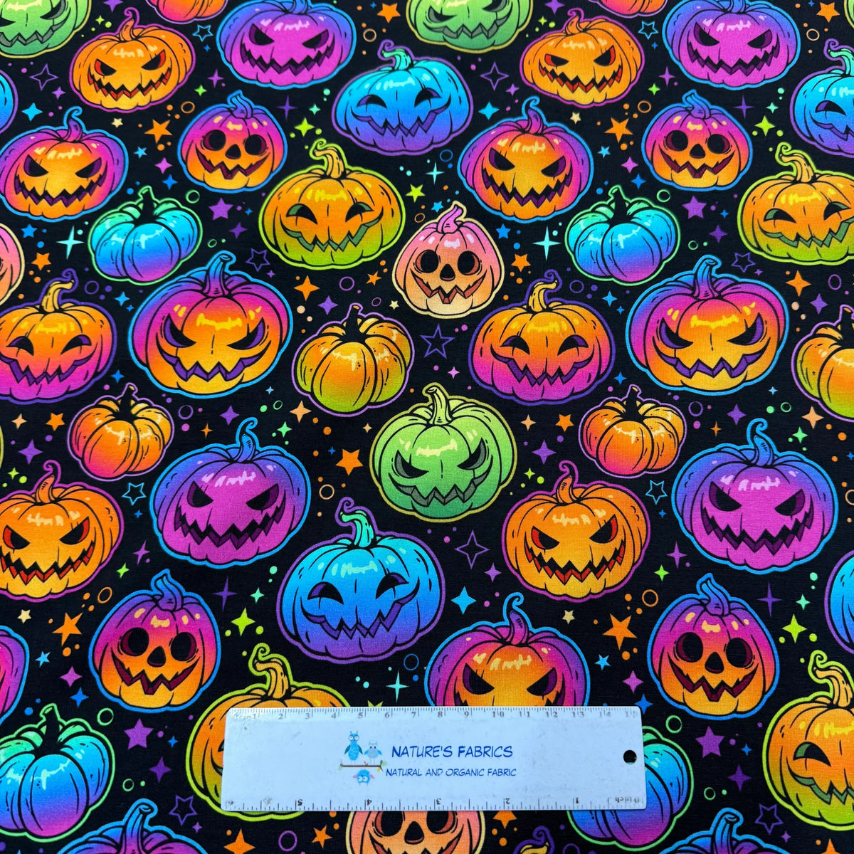 Vibrant Halloween pumpkin fabric by Nature's Fabrics, featuring neon jack-o'-lanterns on black background