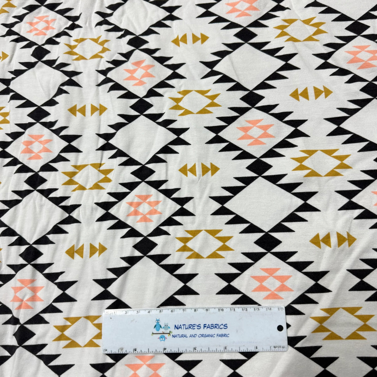 Nature's Fabrics geometric print organic cotton fabric with black, gold, and peach triangles, ruler for scale