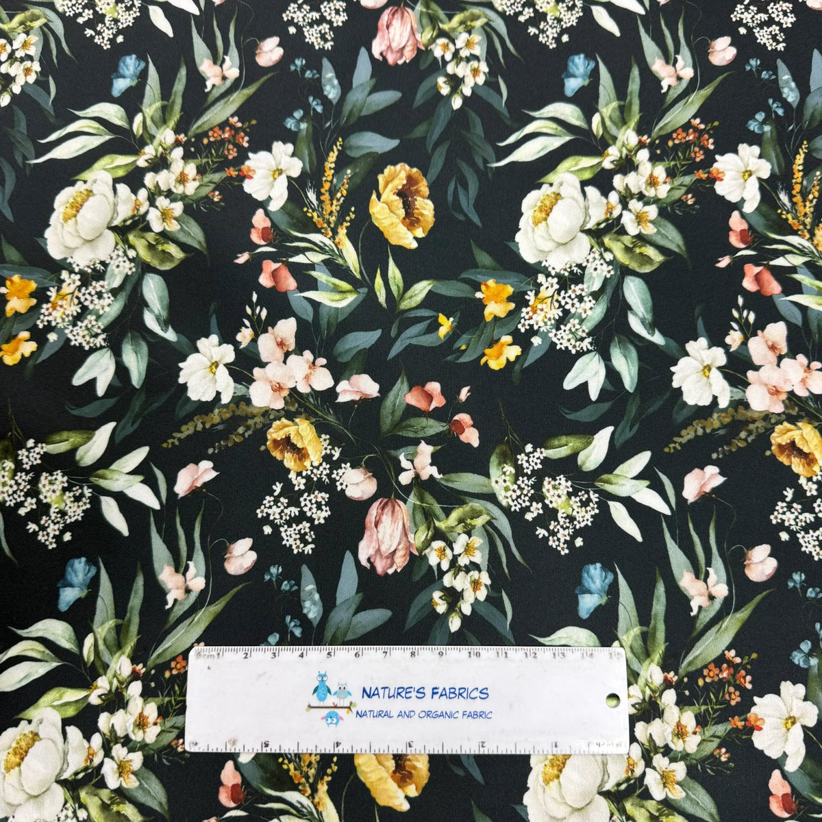 Nature's Fabrics floral print fabric with white, yellow, and pink flowers on dark background