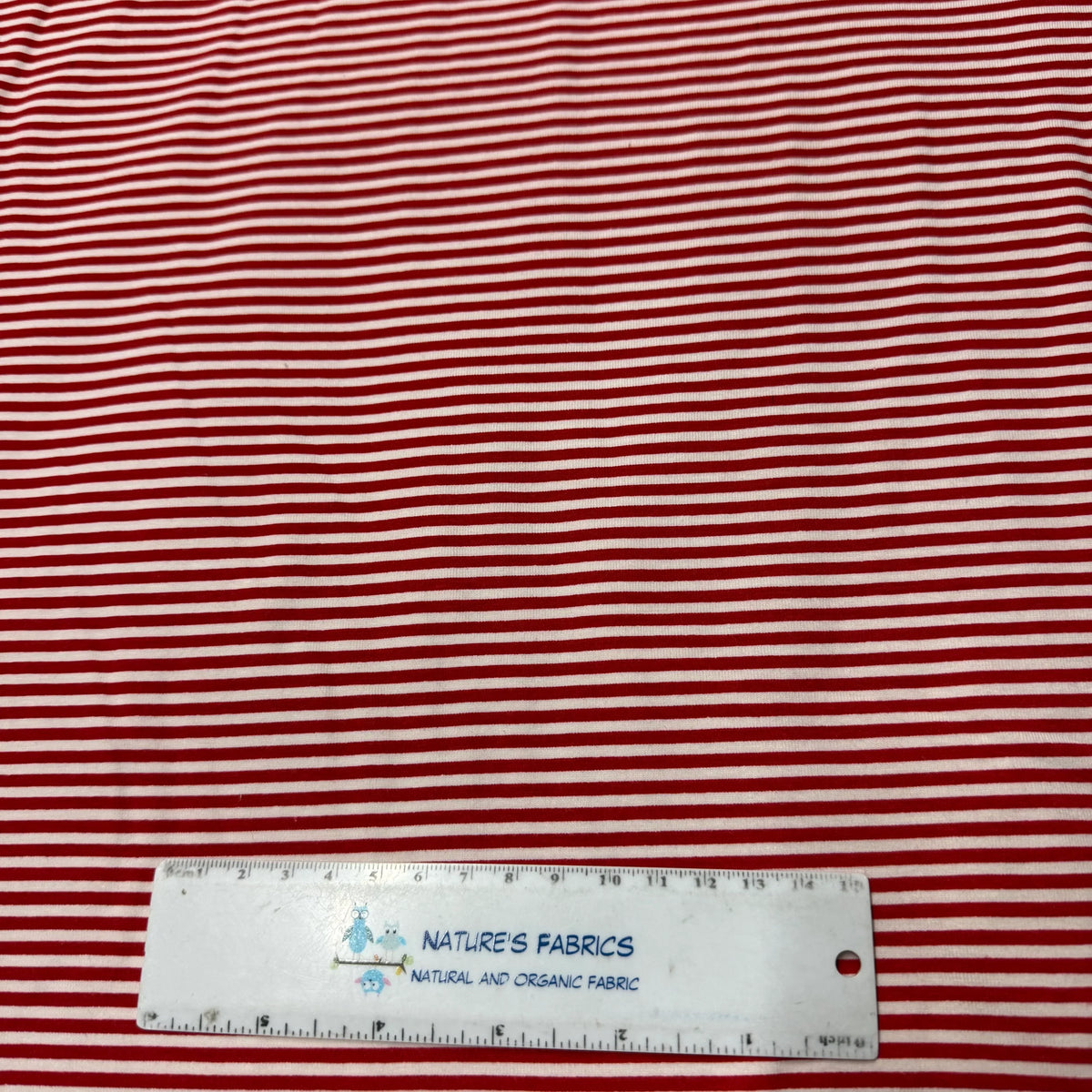 Red and white striped organic cotton fabric from Nature's Fabrics with a ruler for scale.
