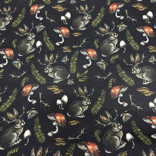 Nature's Fabrics black fabric with a print of jackalopes, mushrooms, and ferns