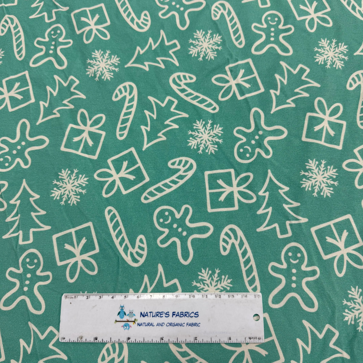 Nature's Fabrics green holiday print with gingerbread, candy canes, snowflakes, and gifts on organic cotton fabric