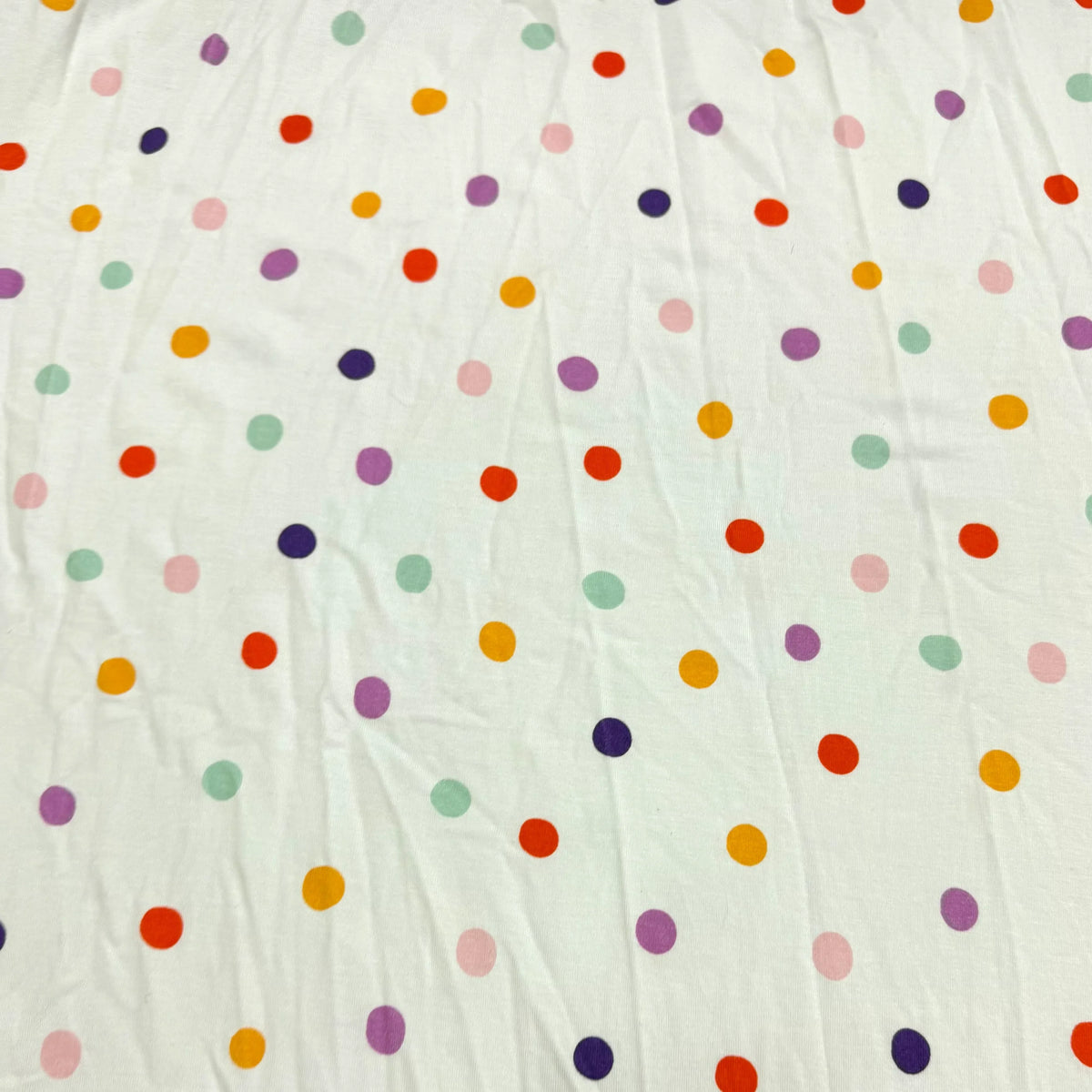 Colorful polka dot fabric by Nature's Fabrics, organic cotton material with rainbow dots on white background