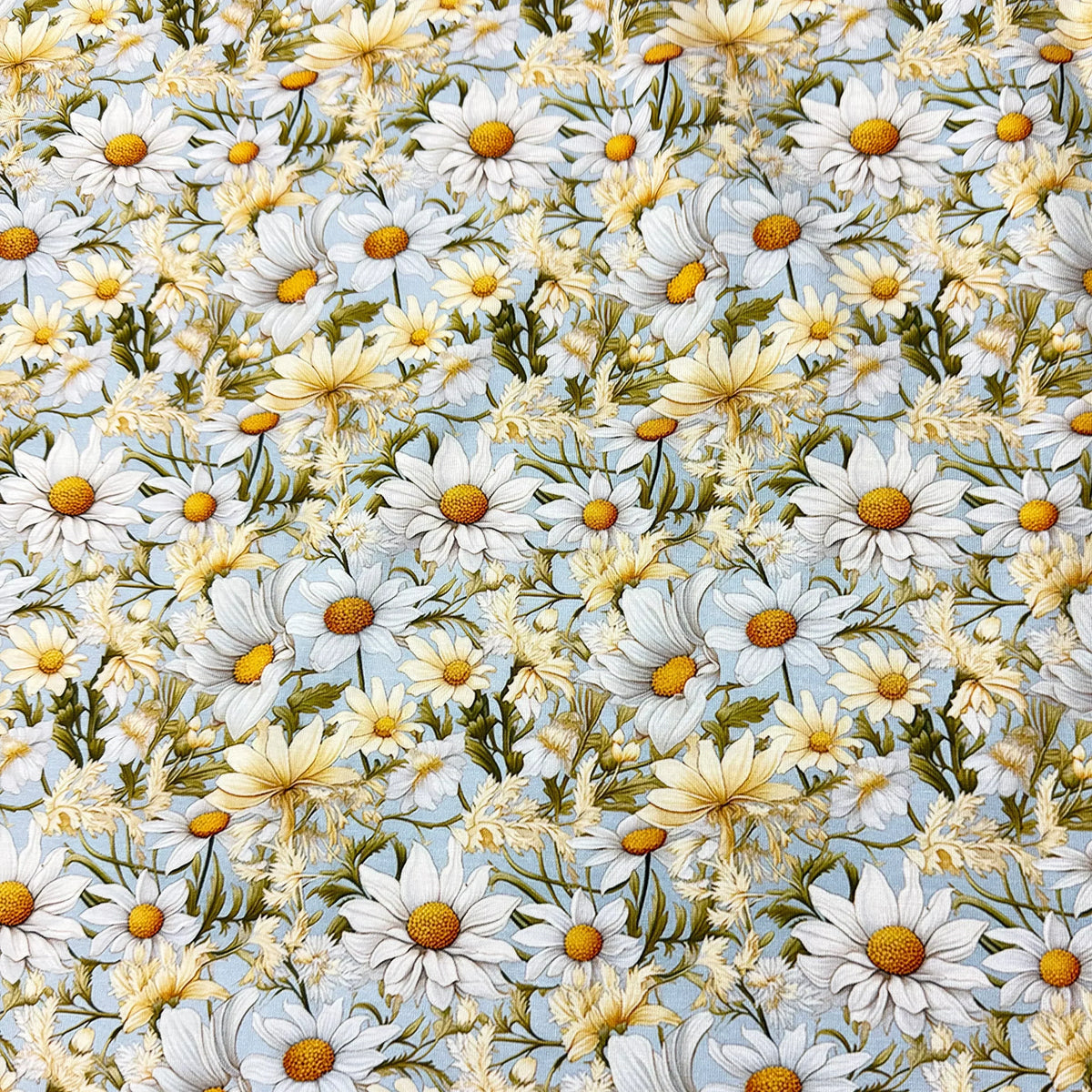 Nature's Fabrics white and yellow daisy floral print fabric on a light blue background
