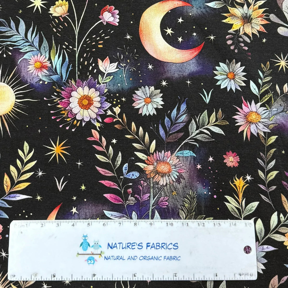 Celestial floral print fabric by Nature's Fabrics with moon, stars, and colorful blooms.