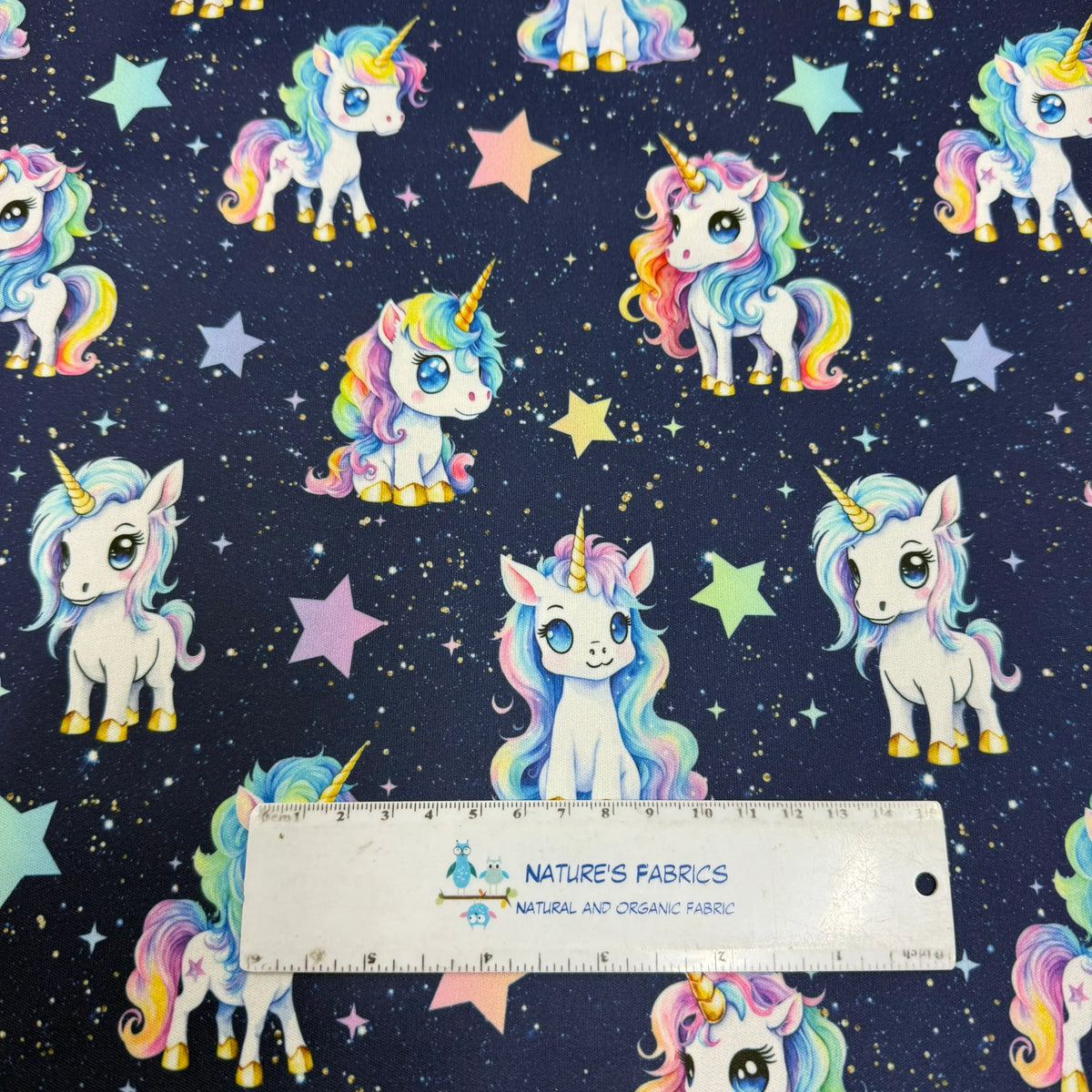 Nature's Fabrics unicorn print fabric with rainbow manes and stars on dark background