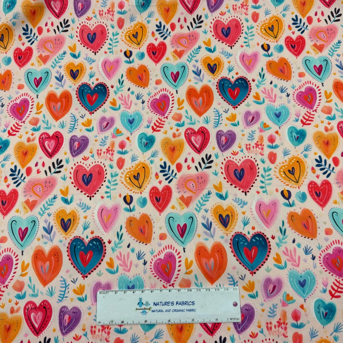 Colorful heart pattern fabric by Nature's Fabrics, featuring vibrant hearts and leaves on natural organic cotton.