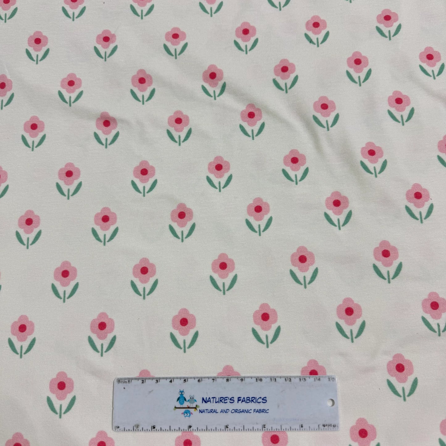 Pink floral print organic cotton fabric by Nature's Fabrics, featuring cute flowers on natural background with ruler for scale