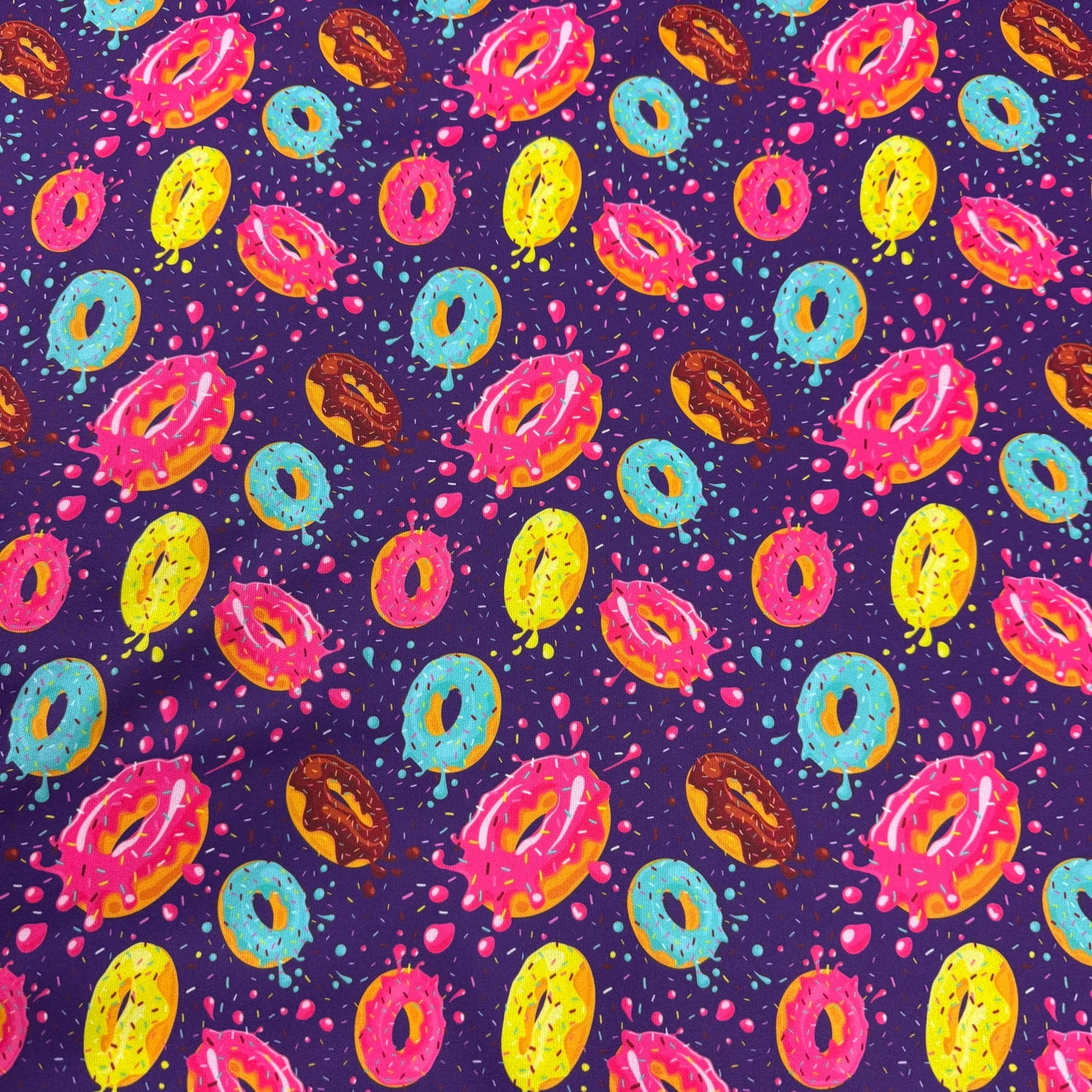 Colorful donut pattern fabric by Nature's Fabrics, featuring vibrant icing and sprinkles on purple background