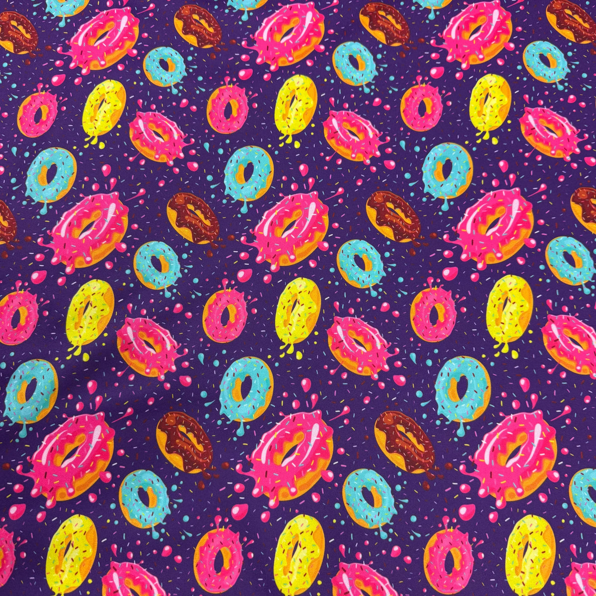 Colorful donut pattern fabric by Nature's Fabrics, featuring vibrant icing and sprinkles on purple background