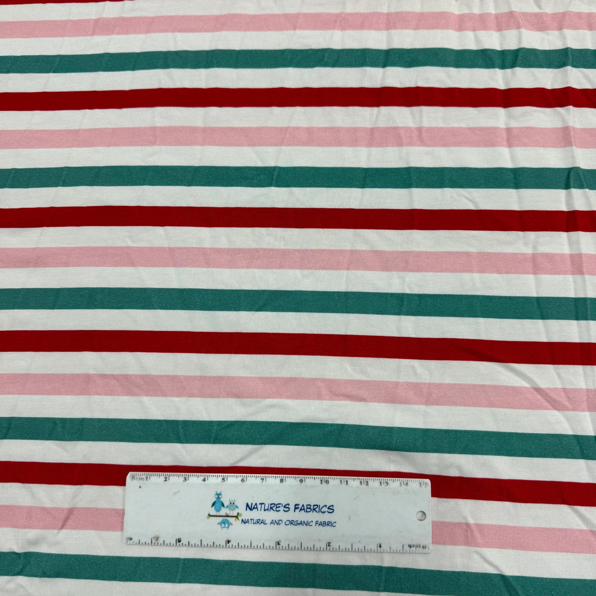 Nature's Fabrics red, green, and pink striped organic cotton fabric with a ruler for scale.