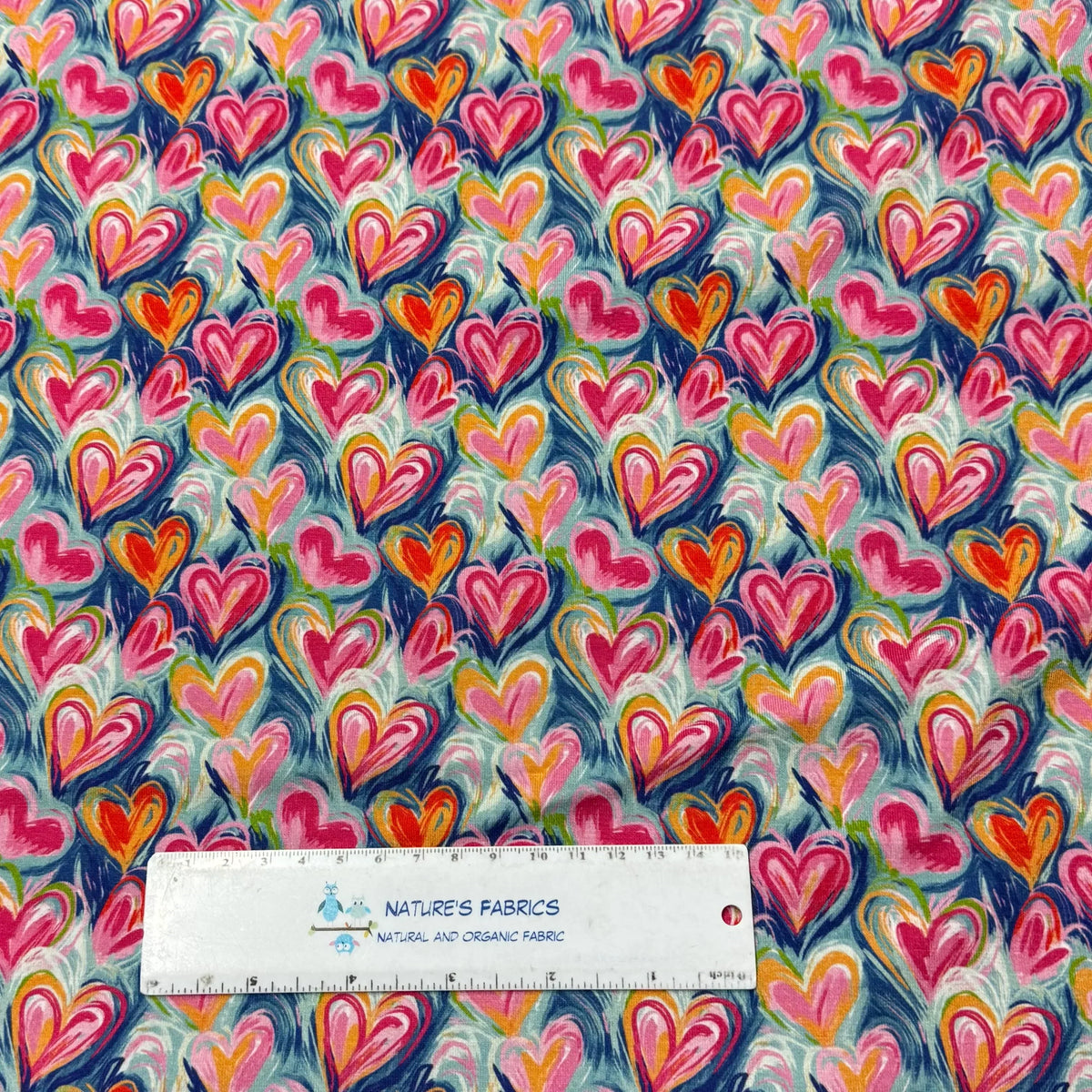 Nature's Fabrics colorful heart print organic cotton fabric with pink, orange, blue swirls and ruler for scale