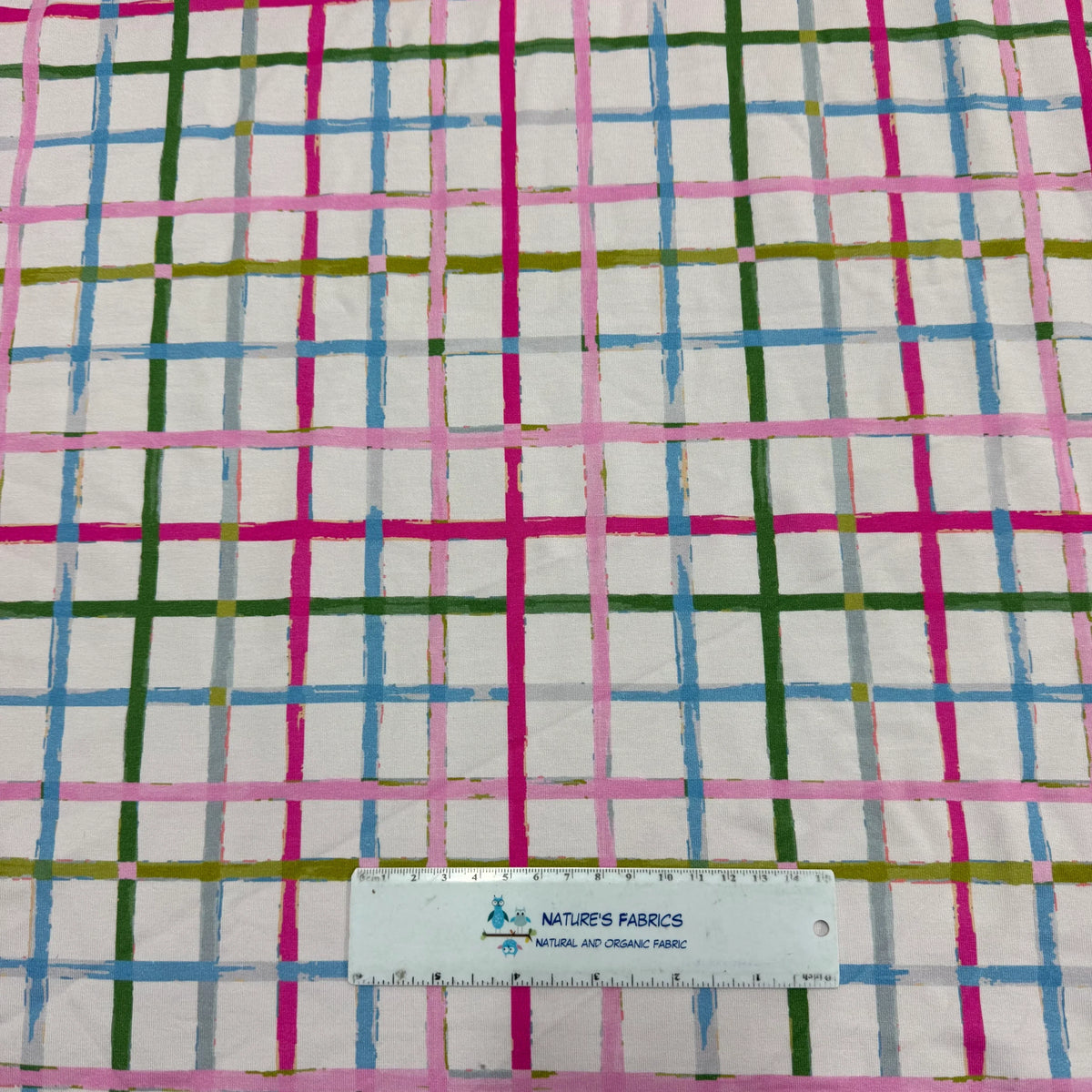 Nature's Fabrics plaid pattern organic cotton fabric with pink, green, blue stripes and ruler for scale