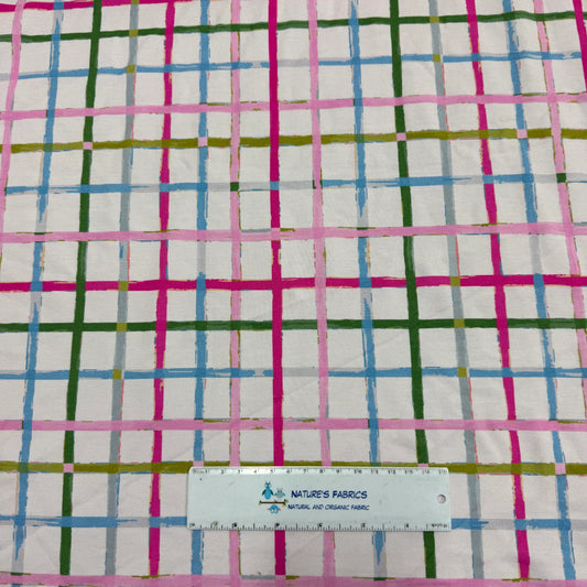 Nature's Fabrics colorful pink, green, and blue plaid patterned organic fabric with a ruler.