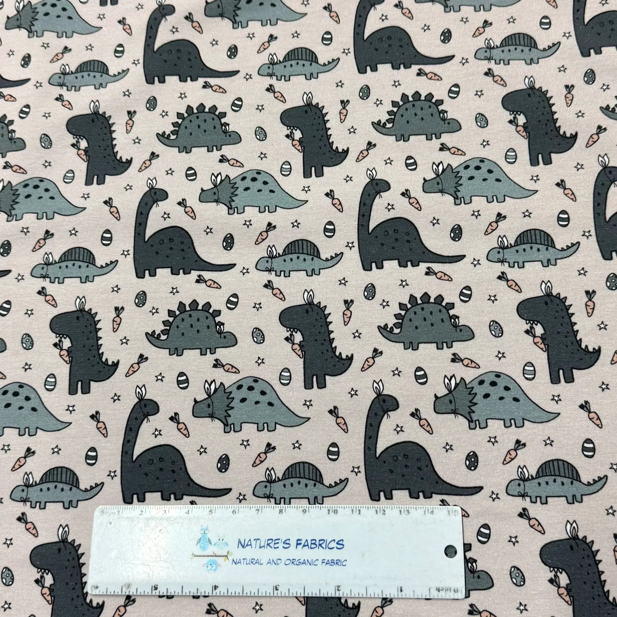 Nature's Fabrics dinosaur print organic cotton fabric with cute grey dinos, carrots, eggs, stars on light background