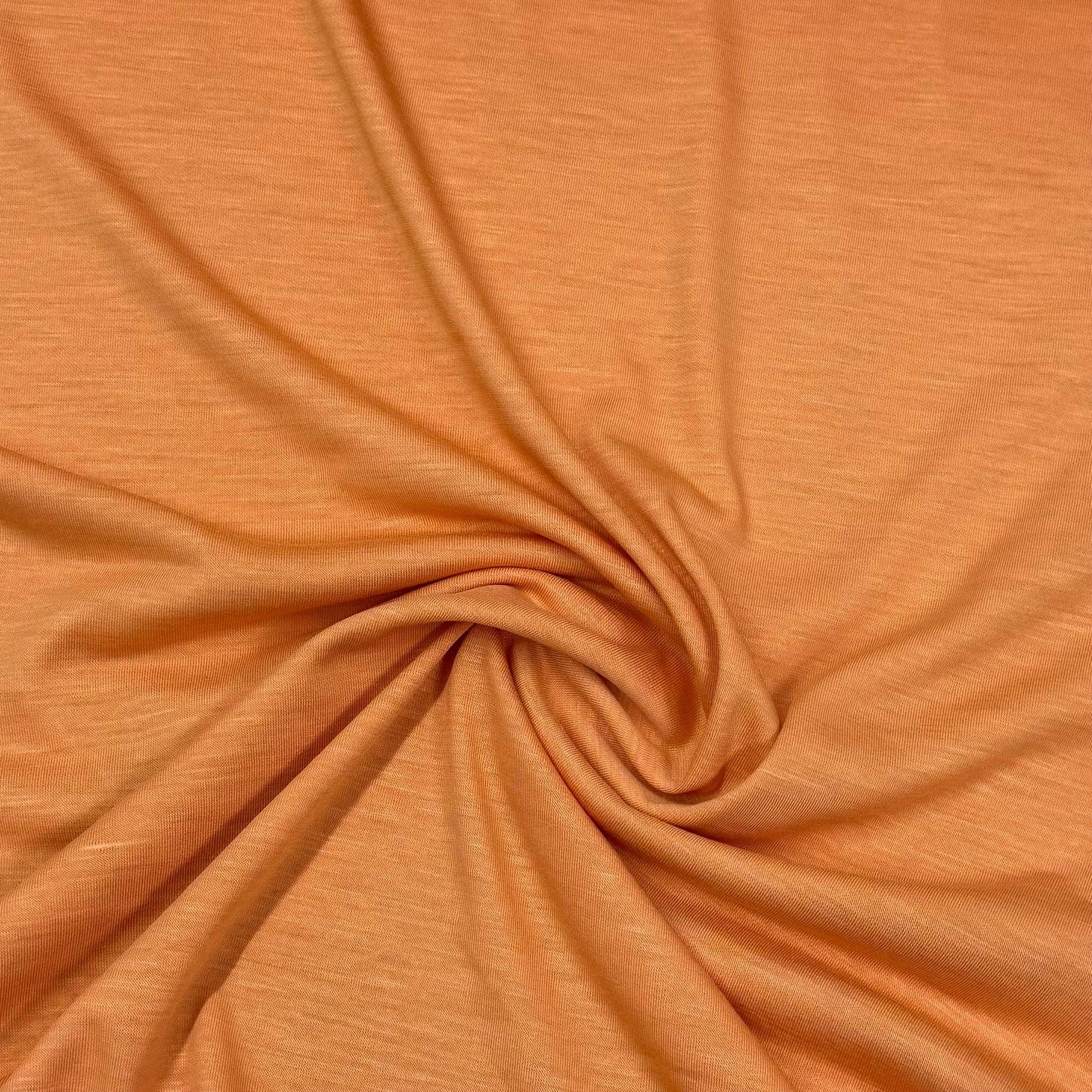Nature's Fabrics organic cotton fabric in warm orange, soft texture with gentle swirl folds