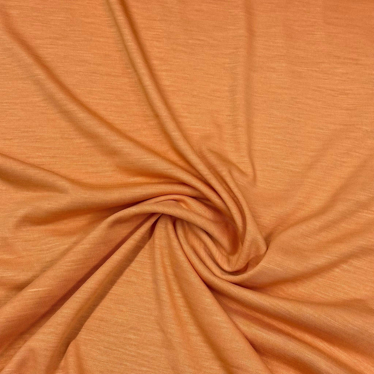 Nature's Fabrics organic cotton fabric in warm orange, soft texture with gentle swirl folds