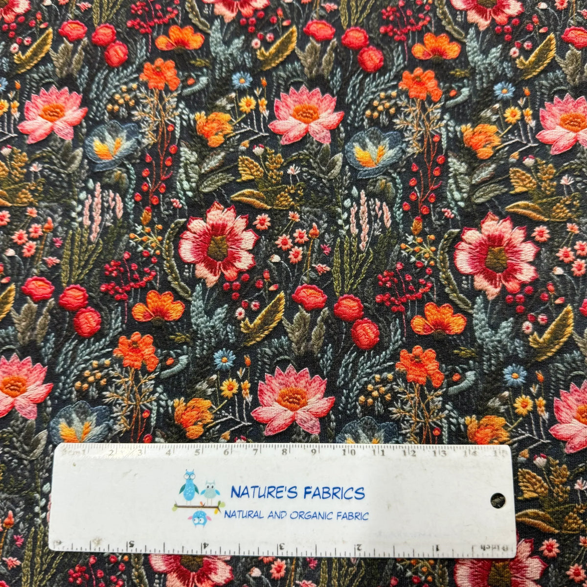 Nature's Fabrics dark floral printed organic cotton fabric with a ruler for scale.