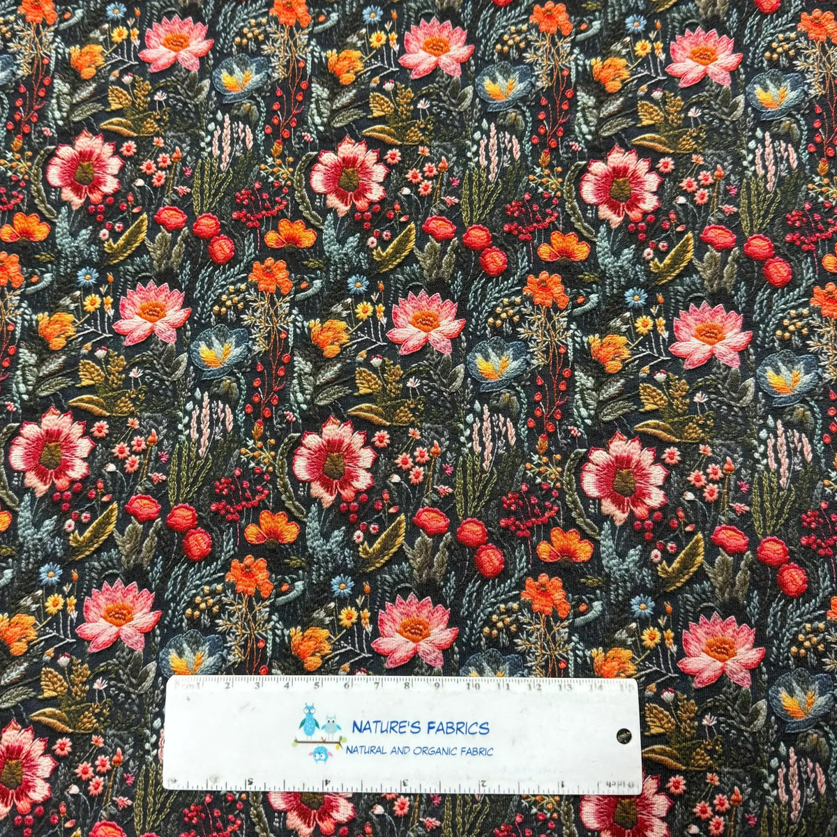 Nature's Fabrics floral print fabric with pink, orange, and blue flowers on dark background, ruler for scale