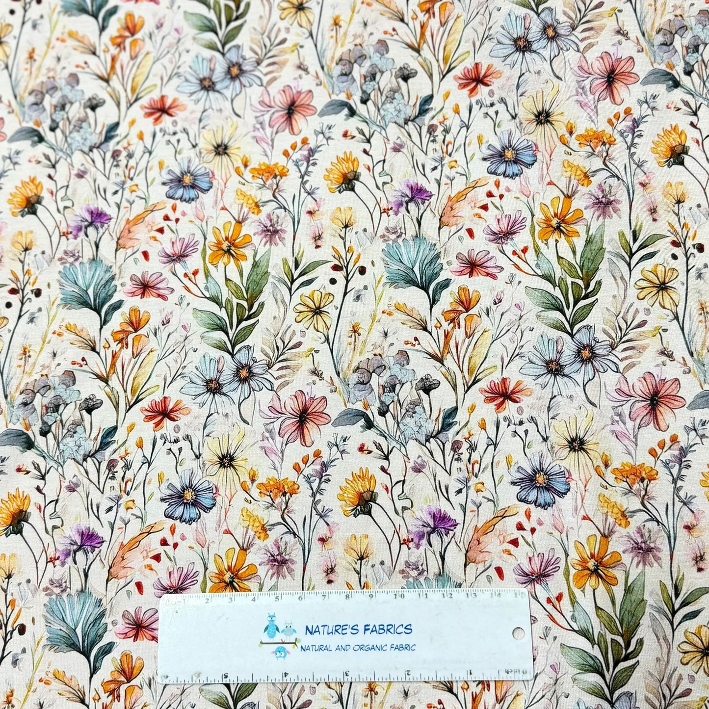 Nature's Fabrics wildflower print organic cotton fabric with colorful blooms and green leaves, eco-friendly textile